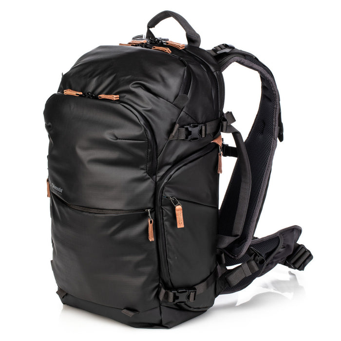 An image of the Shimoda Explore V2 25 Backpack Starter Kit Black. The backpack is black with rust coloured zips and has a carry handle, pockets for water bottles or tripods and multiple zipped pockets with shoulder straps and a removeable belt.