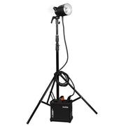 An image of the Godox AD1200Pro TTL Battery Flash Power Pack Kit which contains the Godox AD1200Pro Flash, power pack, 5200mAh battery, 3.65m cable, charger, reflector, glass lamp cover, rolling case, carry case and power cable. The studio flash is pictured set up on a light stand attached to the power pack by a cable.