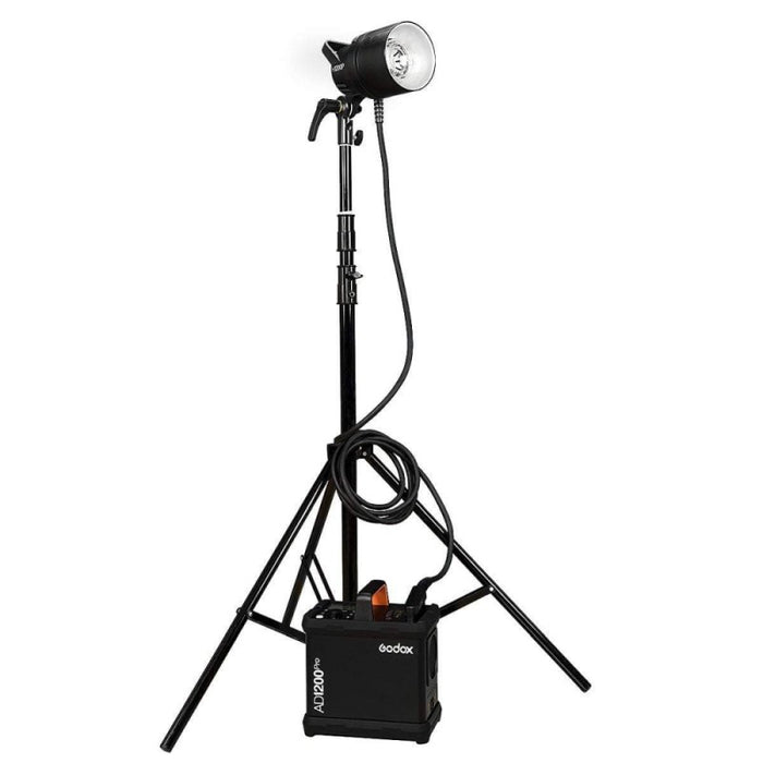 An image of the Godox AD1200Pro TTL Battery Flash Power Pack Kit which contains the Godox AD1200Pro Flash, power pack, 5200mAh battery, 3.65m cable, charger, reflector, glass lamp cover, rolling case, carry case and power cable. The studio flash is pictured set up on a light stand attached to the power pack by a cable.